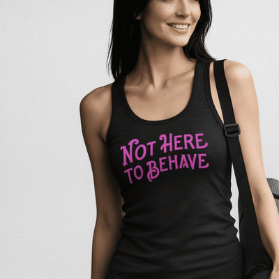 Woman wearing a tank top with 'Not Here To Behave' text, holding a yoga mat.