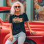 Woman wearing a 'It's a Free Country' t-shirt sitting on a red vintage car.