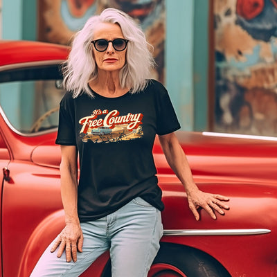 Woman wearing a 'It's a Free Country' t-shirt sitting on a red vintage car.