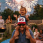 Man with child on shoulders enjoying fireworks in a backyard setting